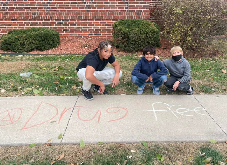 3 young boys next to chalk art that says drug free